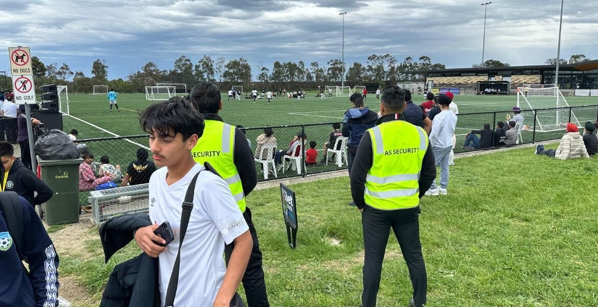 Security personnel in high-visibility vests at a public soccer event, ensuring safety and order for attendees.