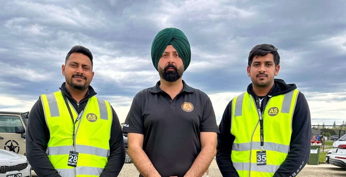 Three security guards from AS Security in Melbourne, wearing high-visibility vests, standing together outdoors with a cloudy sky in the background, showcasing a professional security team.