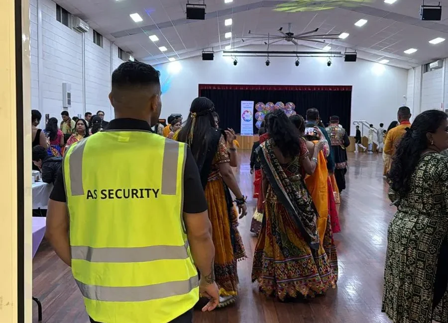 Security personnel in AS Security uniform overseeing a vibrant cultural event with attendees in traditional attire, emphasizing crowd management and safety at the gathering.