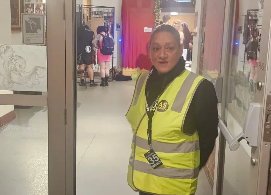 Security personnel in a high-visibility vest standing at an entrance to an event.